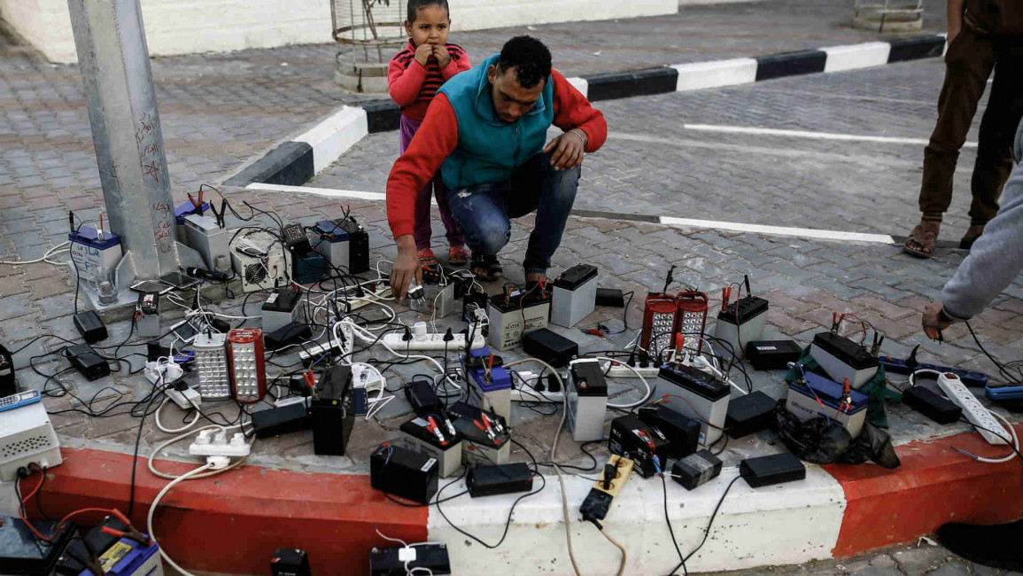  Palestinian charge their mobile phones from batteries
