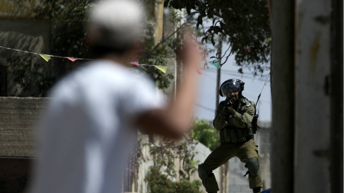 An Israeli soldier aims at a Palestinian protester
