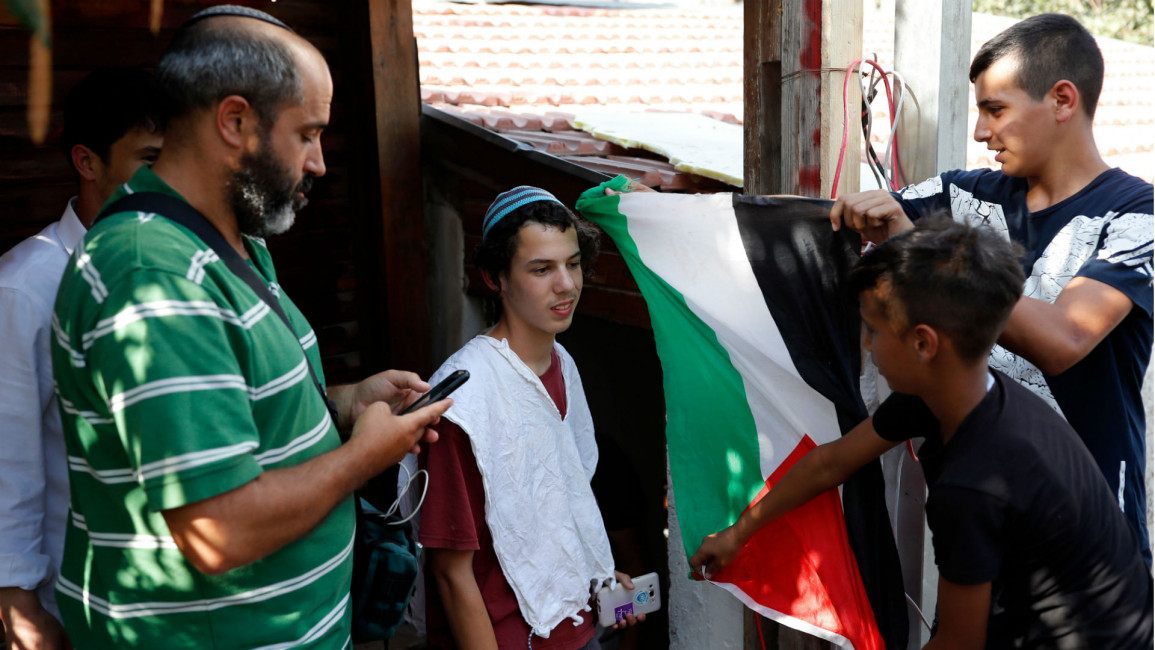 Palestinian youth raise flag Israeli settlers Sheikh Jarrah [GETTY]