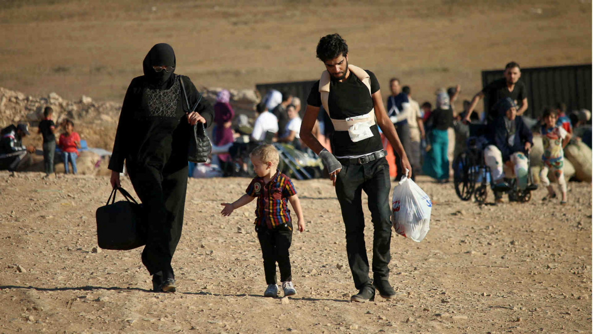 Syrians walk carrying their belongings near Nassib