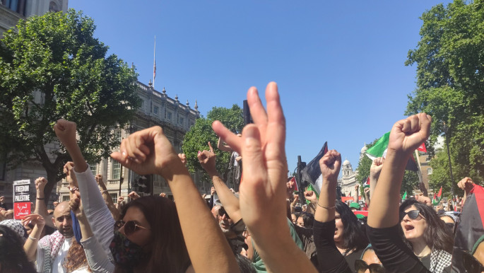 Pro-Palestine protesters raise their fists in the air outside Downing Street in London.