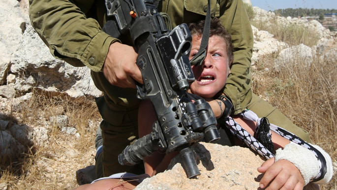 Israeli Soldier 'controls' a Palestinian child